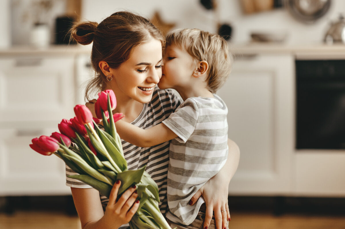 happy mother's day! child son congratulates mother on holiday and gives flowers