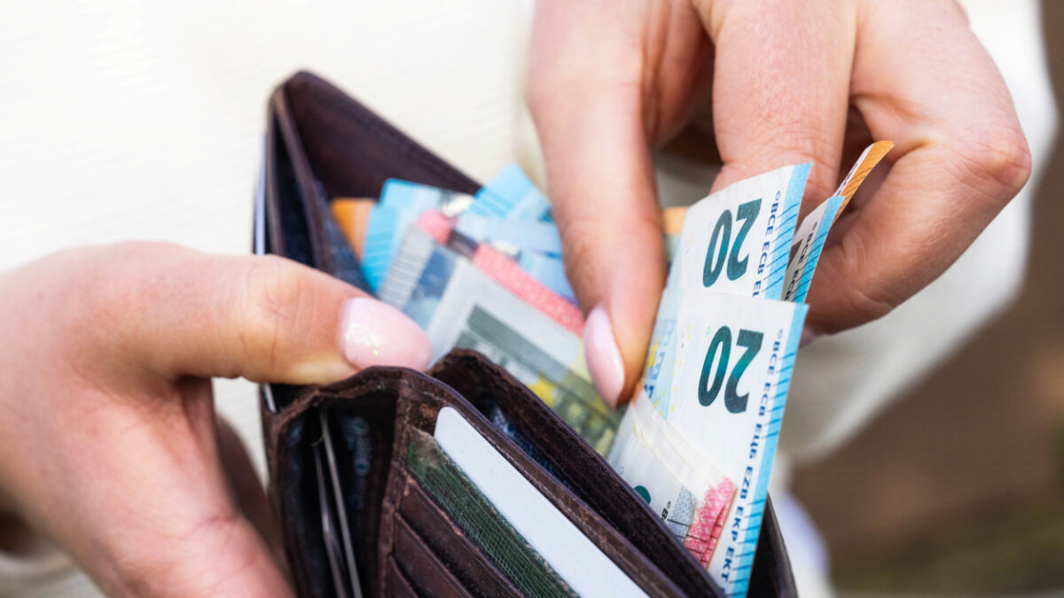 A woman takes Euro banknotes from a leather wallet