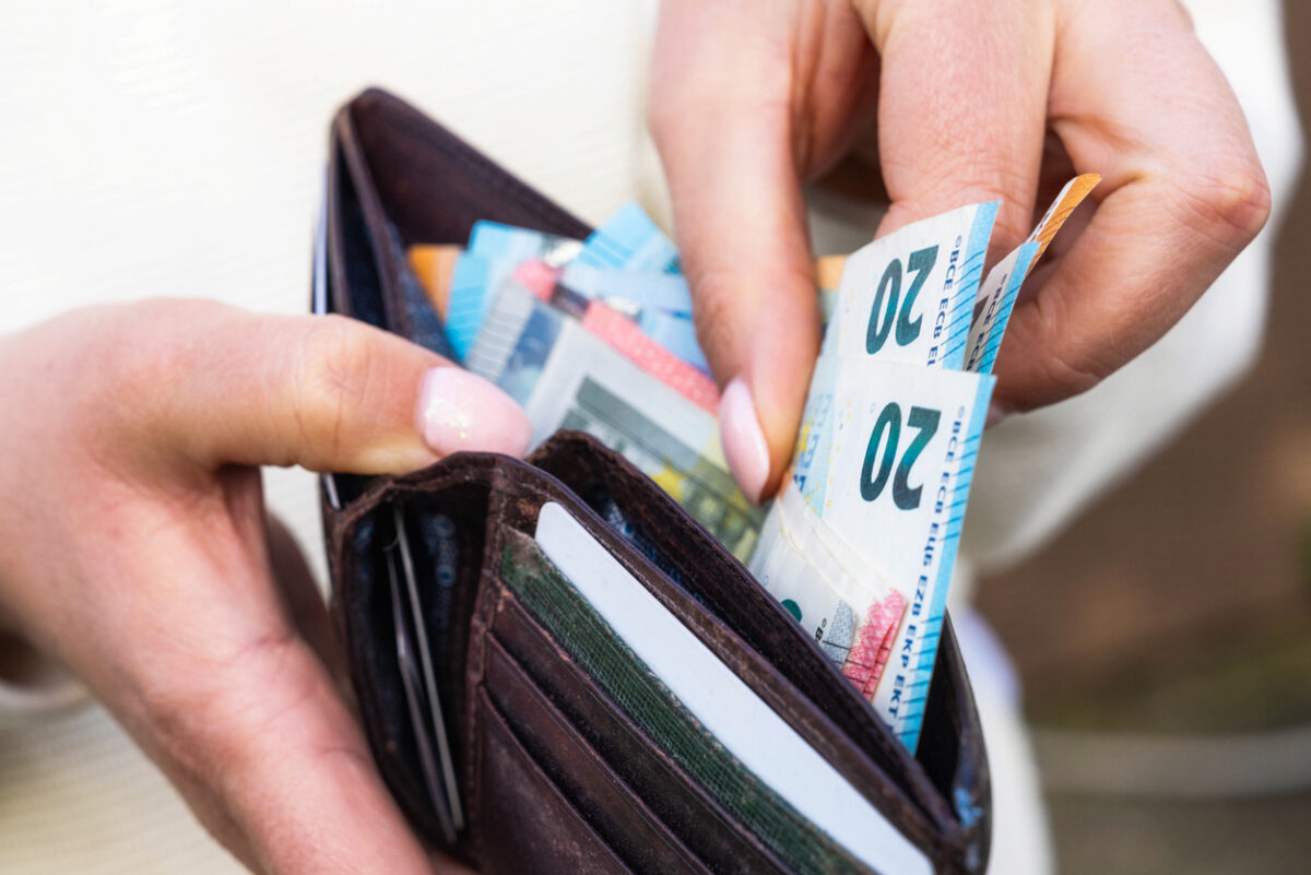 A woman takes Euro banknotes from a leather wallet