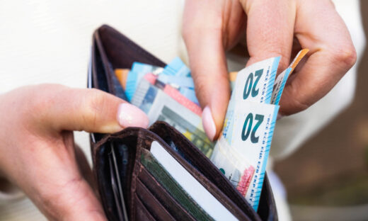 A woman takes Euro banknotes from a leather wallet