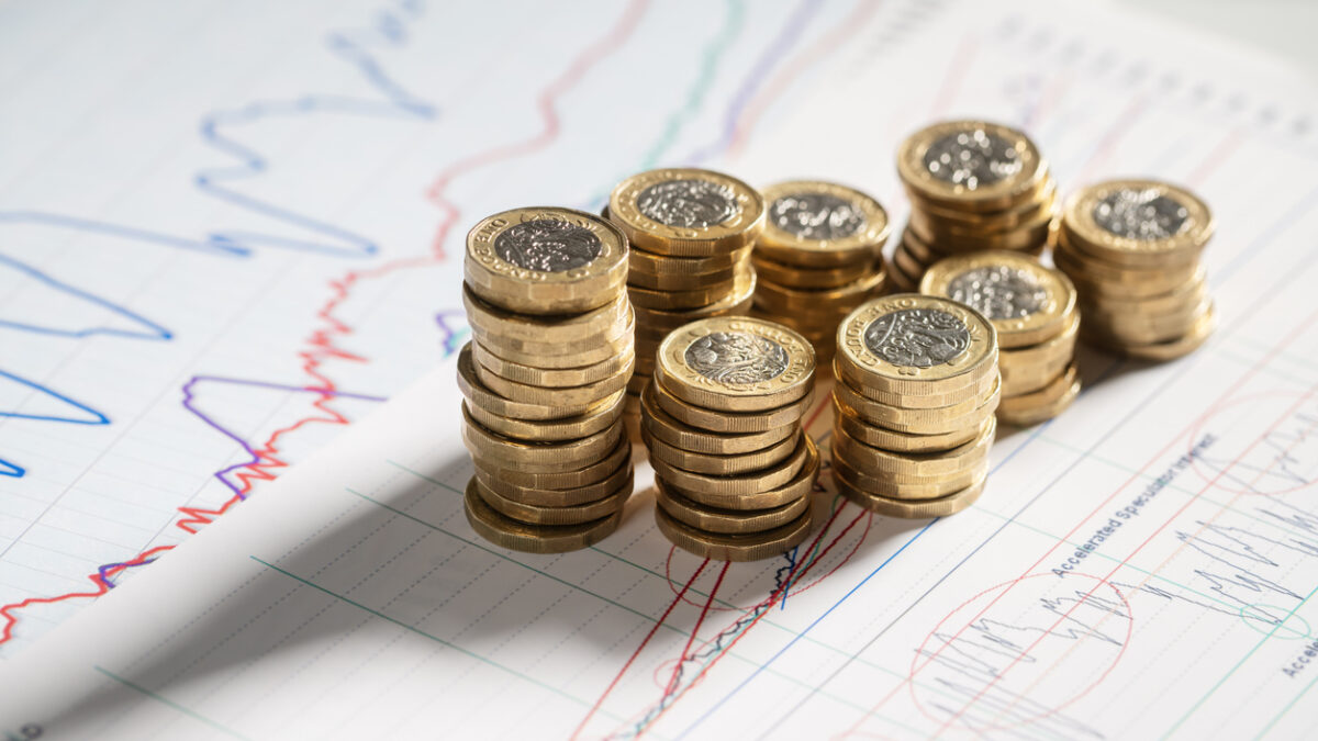 Stack of pound coins on financial graphs and figures