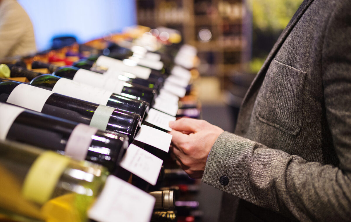 Unrecognizable young man in a wine shop choosing a wine