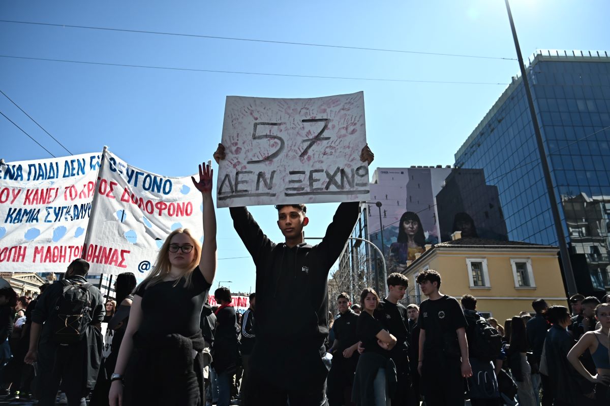 Νεαρός με πλακάτ για τους 57 νεκρούς στα Τέμπη