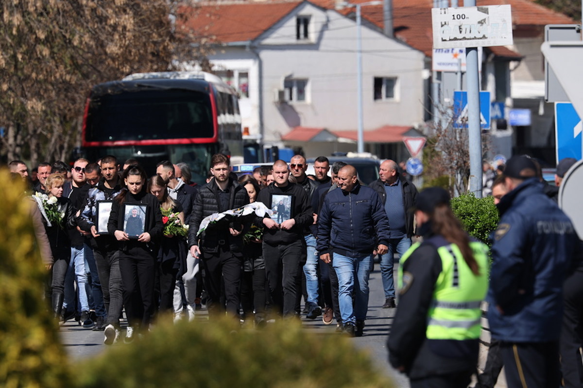 Συγγενείς των θυμάτων κρατούν λουλούδια και φωτογραφιές των δικών τους ανθρώπων που έχασαν τη ζωή τους στην τραγωδία